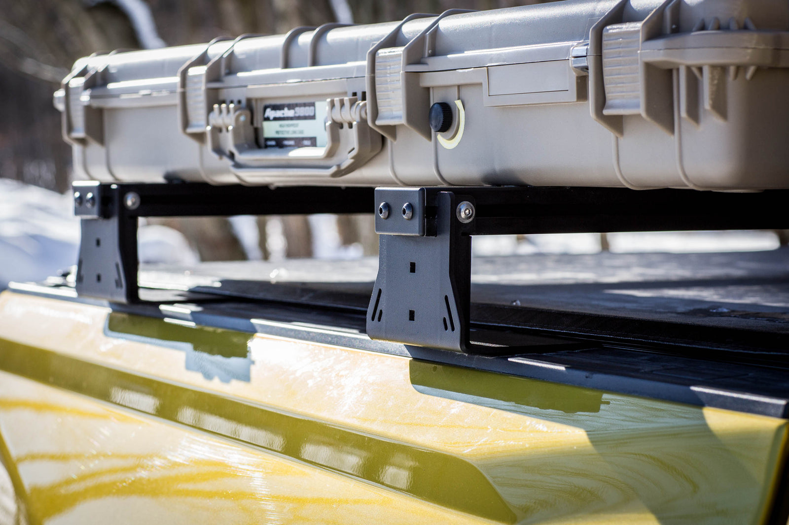 Two large beige cases on a black roof rack with blurred background