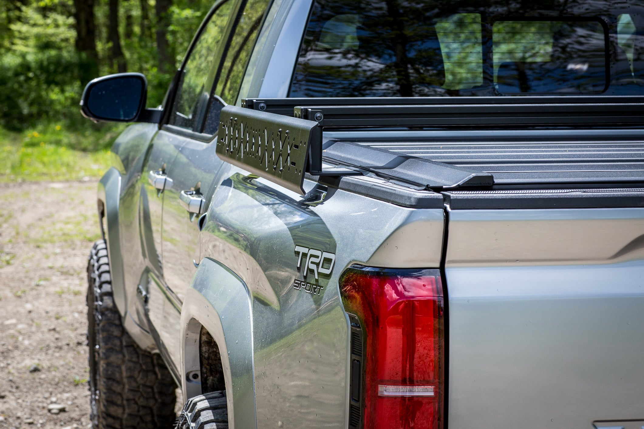 Silver Toyota truck with a tonneau cover in a natural setting