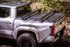 Silver Toyota truck with a tonneau cover in a forest setting